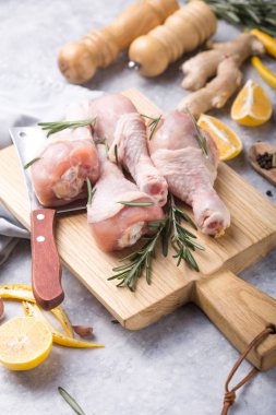 Çiğ organik tavuk budu veya tavada pişirmek için malzemelerle (biber, limon, biberiye, tuz, sarımsak). Et üst görünümü
