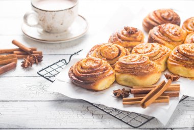 Kahvaltı için latte, kakao ve tarçınlı çörek ya da beyaz arka planda mola. Bir fincan kahve ve ev yapımı çörek.