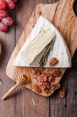 Brie peyniri ya da yumuşak inek dilimi - Fransız peyniri üzümlü, bal peteği ve cevizli ahşap panoda..