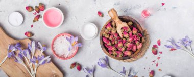 Gri zemin üzerinde deniz tuzu, kuru güller, fırça, yağ ve havlu, pankart, kopyalama alanı, üst görünüm içeren kaplıca ve sağlık kavramı