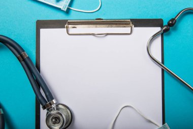 Roman Coronavirus 2019-nCoV konsepti. Tıbbi koruyucu nefes maskesi, steteskop açık mavi arka plan, üst manzara. Grip salgını virüs enfeksiyonu.