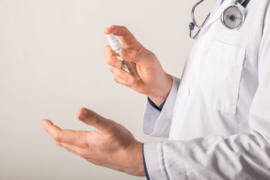 Doktor elleri, beyaz bir arka planda Alkol dezenfektanı ile yıkama elini kullanıyor. 2020 Corona virüs krizinde kendilerini virüs enfeksiyonundan koruyorlar.