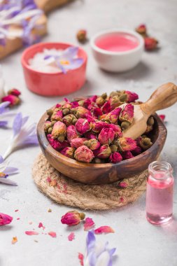 Kuru güller, pembe yağ ve beton arka planda krema içeren kaplıca ve sağlık kavramı.