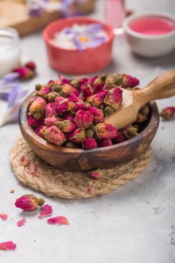 Kuru güller, pembe yağ ve beton arka planda krema içeren kaplıca ve sağlık kavramı.