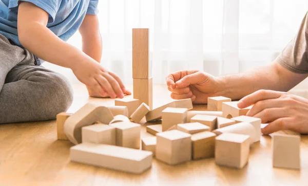 Young dad play with building bricks with small son