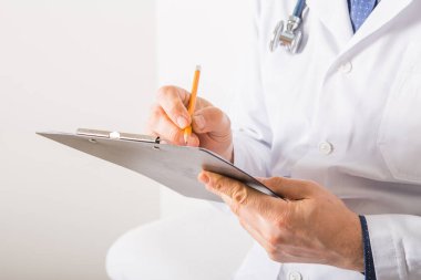 Steteskoplu bir doktor beyaz arka plandaki panoya RX reçetesi yazıyor, yakın plan. Tıbbi hizmet
