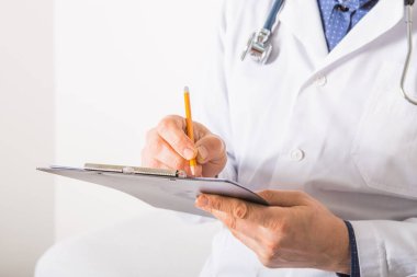 Steteskoplu bir doktor beyaz arka plandaki panoya RX reçetesi yazıyor, yakın plan. Tıbbi hizmet