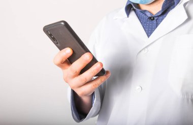 Tıbbi hizmetlerin sağlanmasında mobil cihazlara yardım etme kavramı. Doktor beyaz arka planda bir telefonda çalışıyor. Boşluğu kopyala