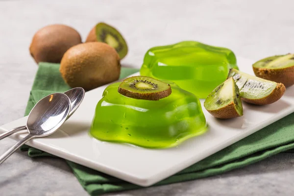 Delicious fresh two green jelly with kiwi slices on concrete table