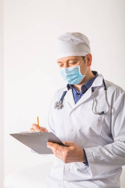 Steteskoplu bir doktor beyaz arka plandaki panoya RX reçetesi yazıyor, yakın plan. Tıbbi hizmet