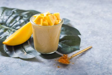 Sarı mango yoğurdu ya da gri arka planda smoothie. Zerdeçal Lassie ya da camdaki Lassi.