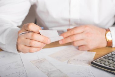 Faturaları kontrol ederken dizüstü bilgisayardaki faturaları analiz eden işadamlarının elleri. Bilgisayarda eşleştirirken Latin adamın faturaları kontrol edişinin arka görünümü. Mali harcamaları hesaplayan adamın elleri.