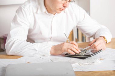 Olgun küçük işletme sahibi, yeni açılan işletmelerin finansal giderlerini hesaplamak ve hesaplamak için dizüstü bilgisayar ve hesap makinesi kullanan girişimci