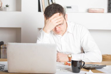 İş adamının ofiste çalışan dizüstü bilgisayarla strese girmesi, Kafkasyalı adamın kafasına dokunması, kötü bir baş ağrısı, stres ve aşırı çalışma konsepti var..
