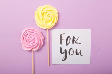 Sarı ve pembe renkli pastel renkli şekerler ahşap bir çubukta üzerinde 