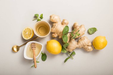 Ballı zencefilli limon çayı. Narenciye ve zencefille çayı ısıtıyorum. Bardak, bal, gri pastel arka planda zencefil kökü, kopyalama alanı, üst görünüm.