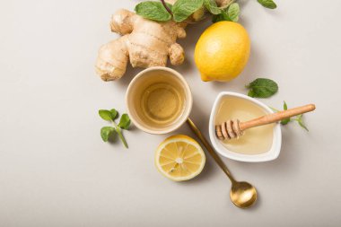 Ballı zencefilli limon çayı. Narenciye ve zencefille çayı ısıtıyorum. Bardak, bal, gri pastel arka planda zencefil kökü, kopyalama alanı, üst görünüm.