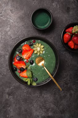 Renkli, sağlıklı yiyecekler. Acai smoothie kasesi. Keto kahvaltı fikri. Meyveli buzlu içecek, acai. Yeşil spirulinalı kahvaltı, çilek, chia, kivi siyah tabakta.