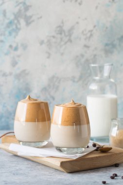 Dalgona Köpüklü Kahve, mavi beton masanın üzerinde çırpılmış kahve, şeker ve süt bulunan bir Güney Kore içeceğidir.