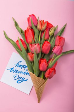 Dondurma külahında kırmızı, güzel laleler ve renkli bir kartın içinde. Kavramsal bir çiçek hediyesi fikri. Bahar havası