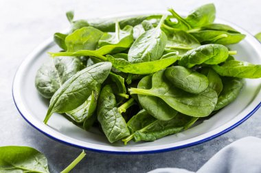 Bebek ıspanak yaprakları gri beton arka planda, üst manzara, kopyalama alanı. Temiz yemek, detoks, diyet gıda malzemeleri.
