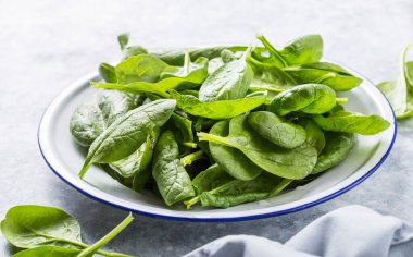 Bebek ıspanak yaprakları gri beton arka planda, üst manzara, kopyalama alanı. Temiz yemek, detoks, diyet gıda malzemeleri.
