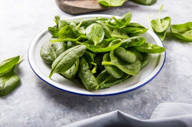 Bebek ıspanak yaprakları gri beton arka planda, üst manzara, kopyalama alanı. Temiz yemek, detoks, diyet gıda malzemeleri.