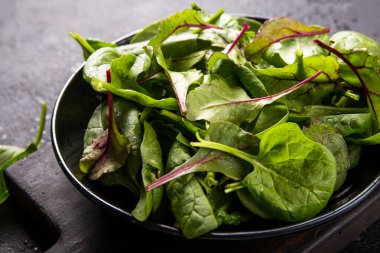 Bebek ıspanak, pancar yaprağı, siyah beton arka plan, üst manzara, kopyalama alanı. Temiz yemek, detoks, diyet gıda malzemeleri.