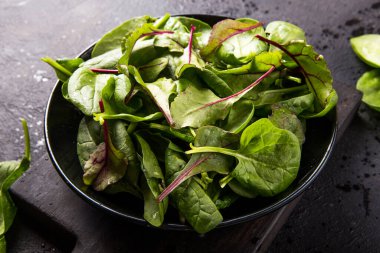 Bebek ıspanak, pancar yaprağı, siyah beton arka plan, üst manzara, kopyalama alanı. Temiz yemek, detoks, diyet gıda malzemeleri.