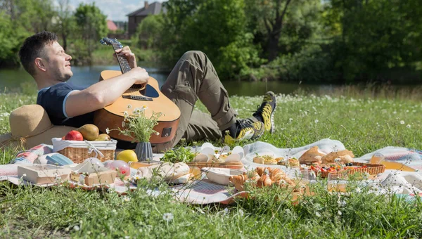 ピクニックをしていると公園 週末楽しんで幸せな友達 食べ物や飲み物 面白い活動 若者のライフ スタイルのコンセプトのグループでギターを弾く若者 — ストック写真