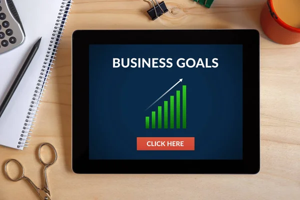 Business goals concept on tablet screen with office objects