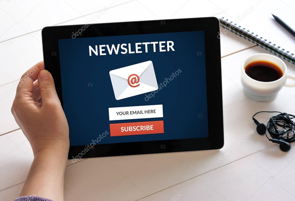 Hand holding tablet with subscribe newsletter concept on screen.