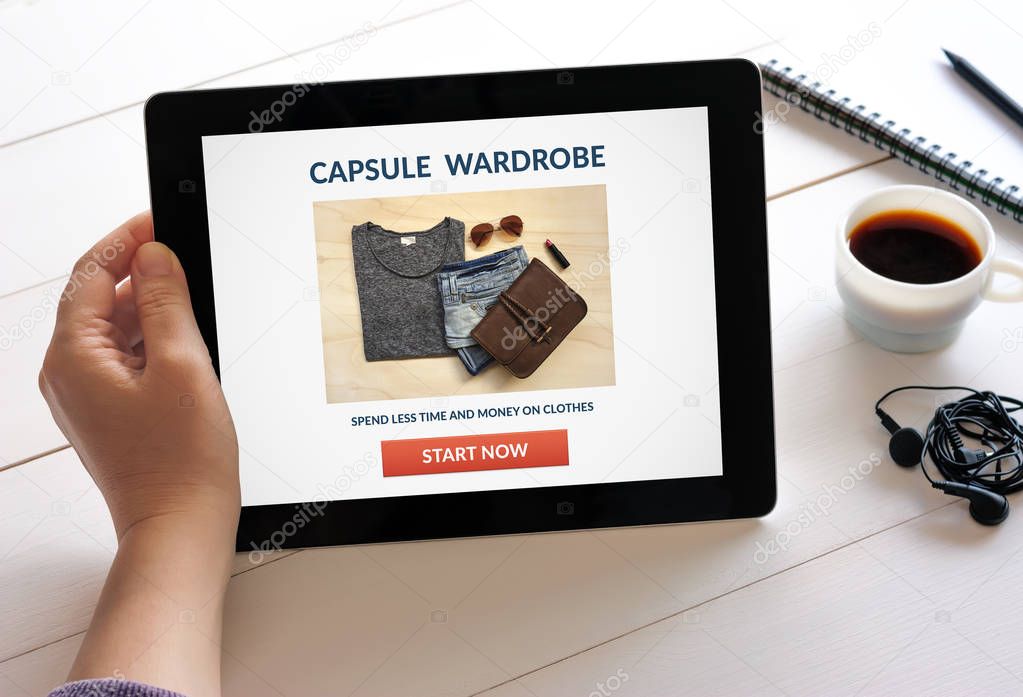 Hand holding tablet with capsule wardrobe concept on screen