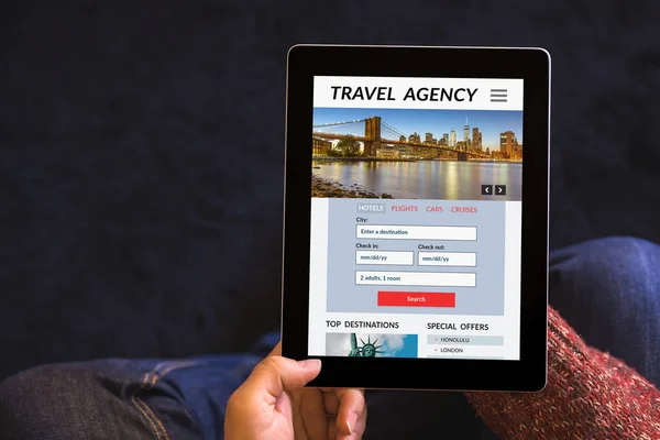 Hands holding tablet with travel agency concept on screen