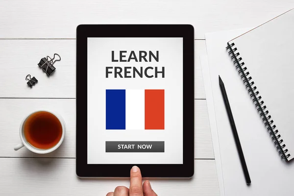 Learn French concept on tablet screen with office objects