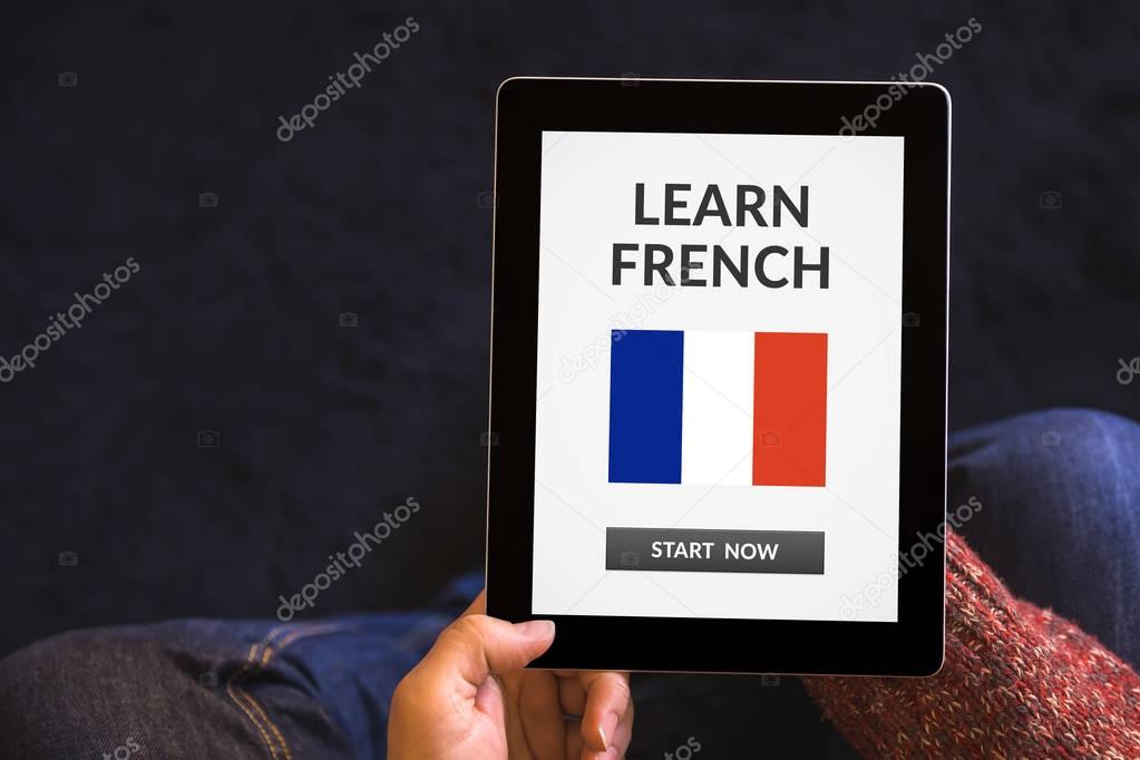 Hands holding tablet with learn French concept on screen