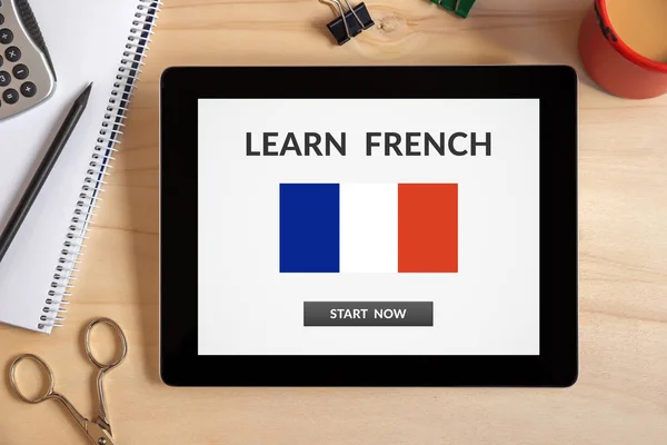 Learn French concept on tablet screen with office objects