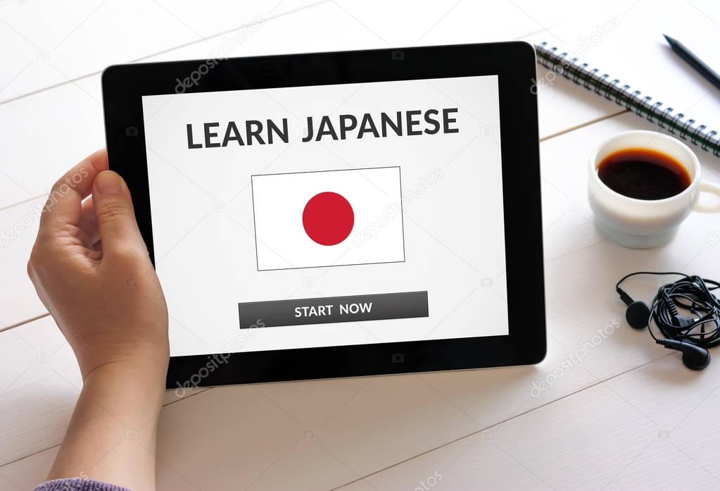 Hand holding tablet with learn Japanese concept on screen