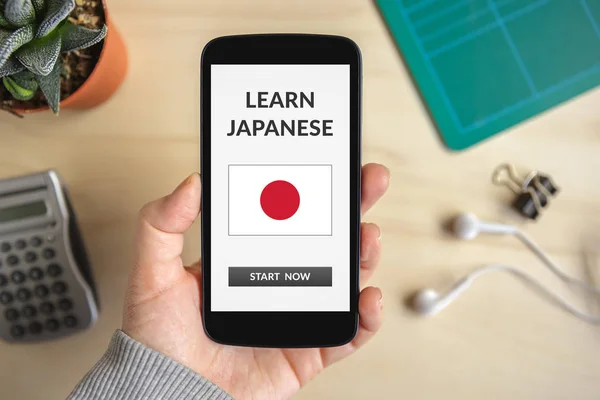 Hand holding smart phone with learn Japanese concept on screen