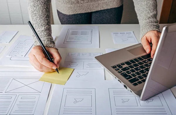 Web designer working at laptop and website wireframe sketches — Stock Photo, Image