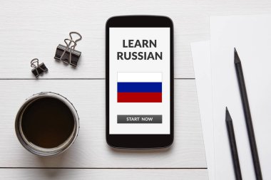 Rus konsepti üzerine beyaz ahşap masa akıllı telefonun ekranında öğrenin