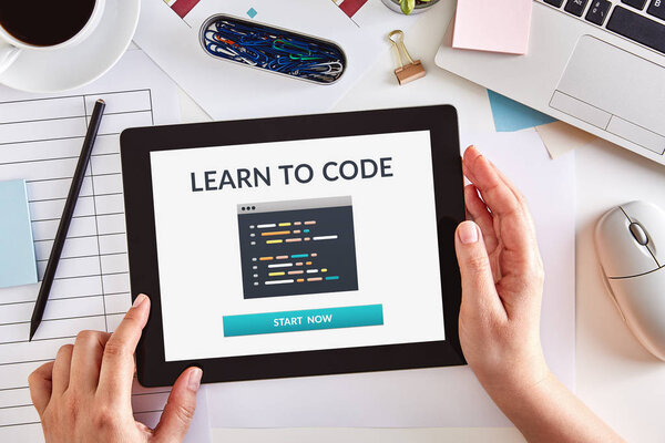 Hands using tablet with learn to code concept on screen