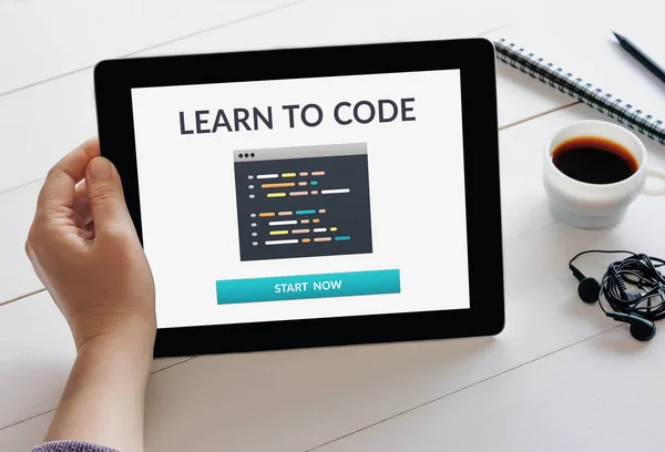 Hand holding tablet with learn to code concept on screen — 스톡 사진