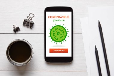 Coronavirus, beyaz ahşap masada ofis eşyalarıyla akıllı telefon ekranında covid-19 konsepti. Üst görünüm