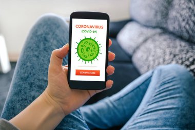 Koronavirüslü akıllı telefonu elinde tutan bir kız. Ekranda Coperid-19 konsepti. Sosyal uzaklık 