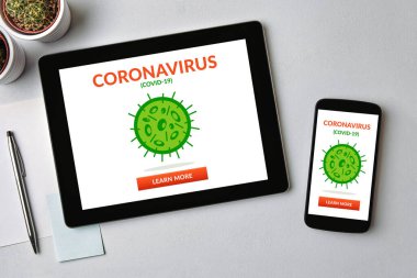 Coronavirus, tablet üzerinde covid-19 konsepti ve gri masanın üzerinde cep telefonu ekranı. Sosyal uzaklık. Üst görünüm