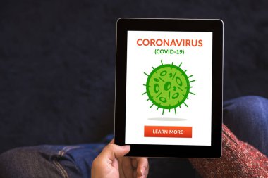Eller koronavirüslü dijital tablet bilgisayarı tutuyor. Ekranda covid-19 konsepti var. Üst görünüm