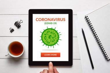 Coronavirus, beyaz ahşap masadaki ofis eşyalarıyla dolu tablet ekranda covid-19 konsepti. Sosyal uzaklık. Üst görünüm