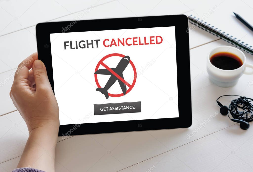 Hand holding digital tablet computer with flight cancelled concept on screen.