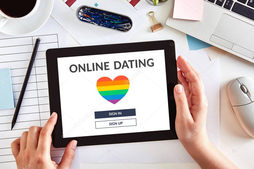 Hands using a digital tablet computer with LGBT dating app concept on screen over business desk. Gay online dating. Top view